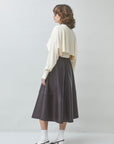 Woman wearing a white blouse and dark skirt on a plain background