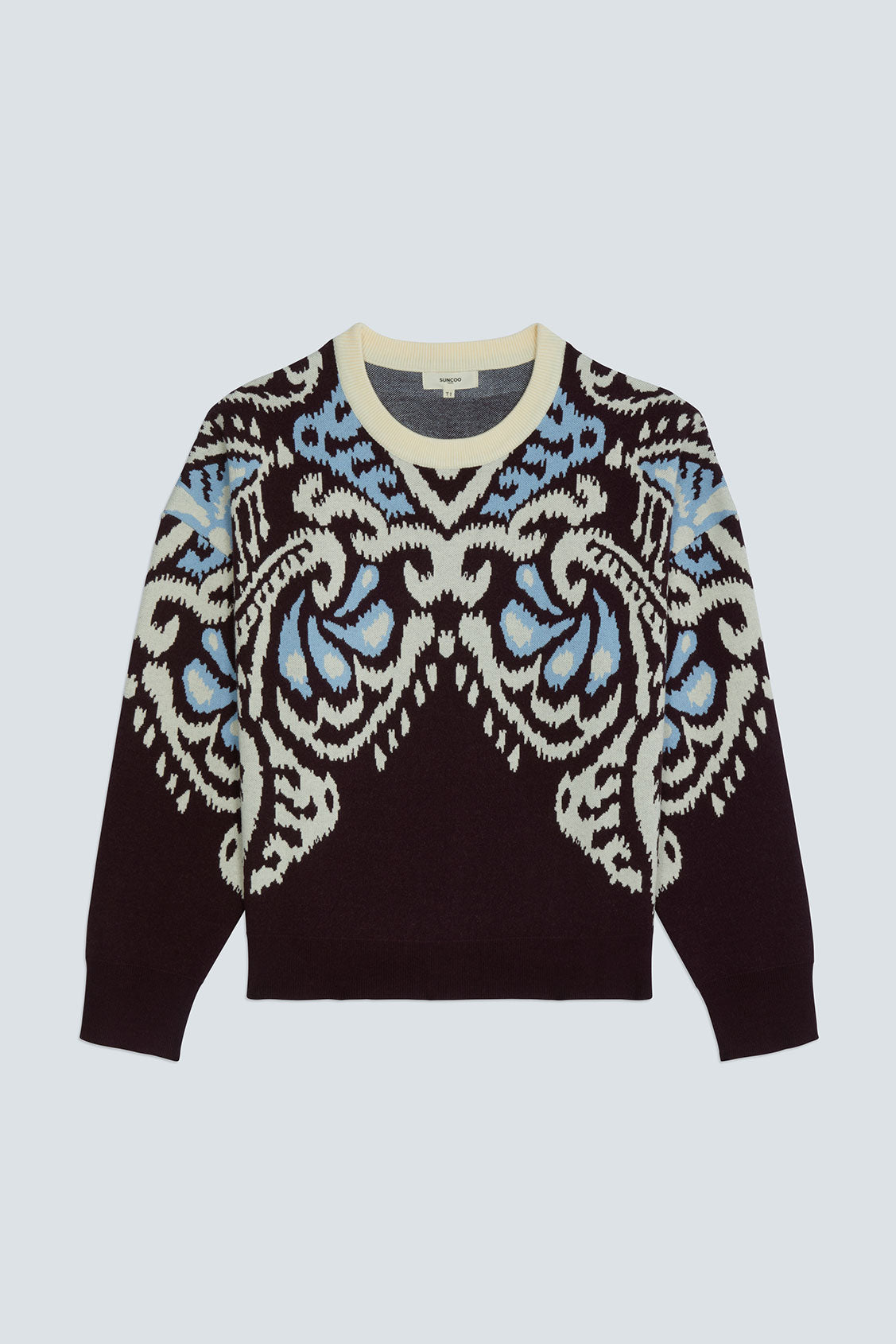 A long-sleeve crewneck sweater featuring a dark brown base with a large, symmetrical ikat-style pattern in cream and light blue across the chest and shoulders, displayed on a light gray background.