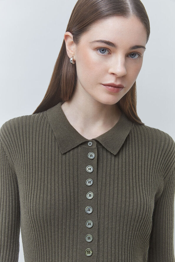 A woman wearing a ribbed knit polo-style top in olive green with a button-front placket, photographed against a light gray studio background.