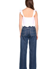 Woman wearing blue jeans and a white top on a white background, back view