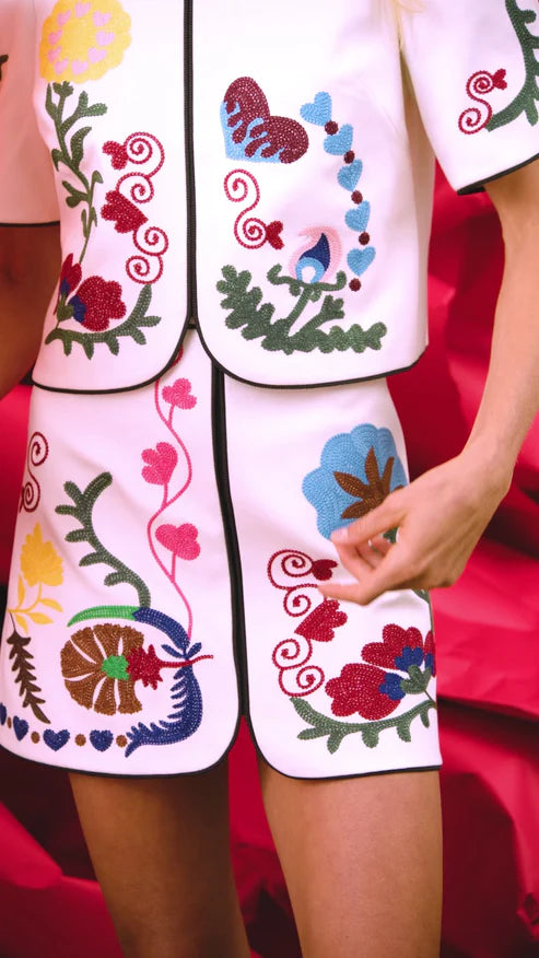 Embroidered outfit with colorful floral and butterfly designs on a red background