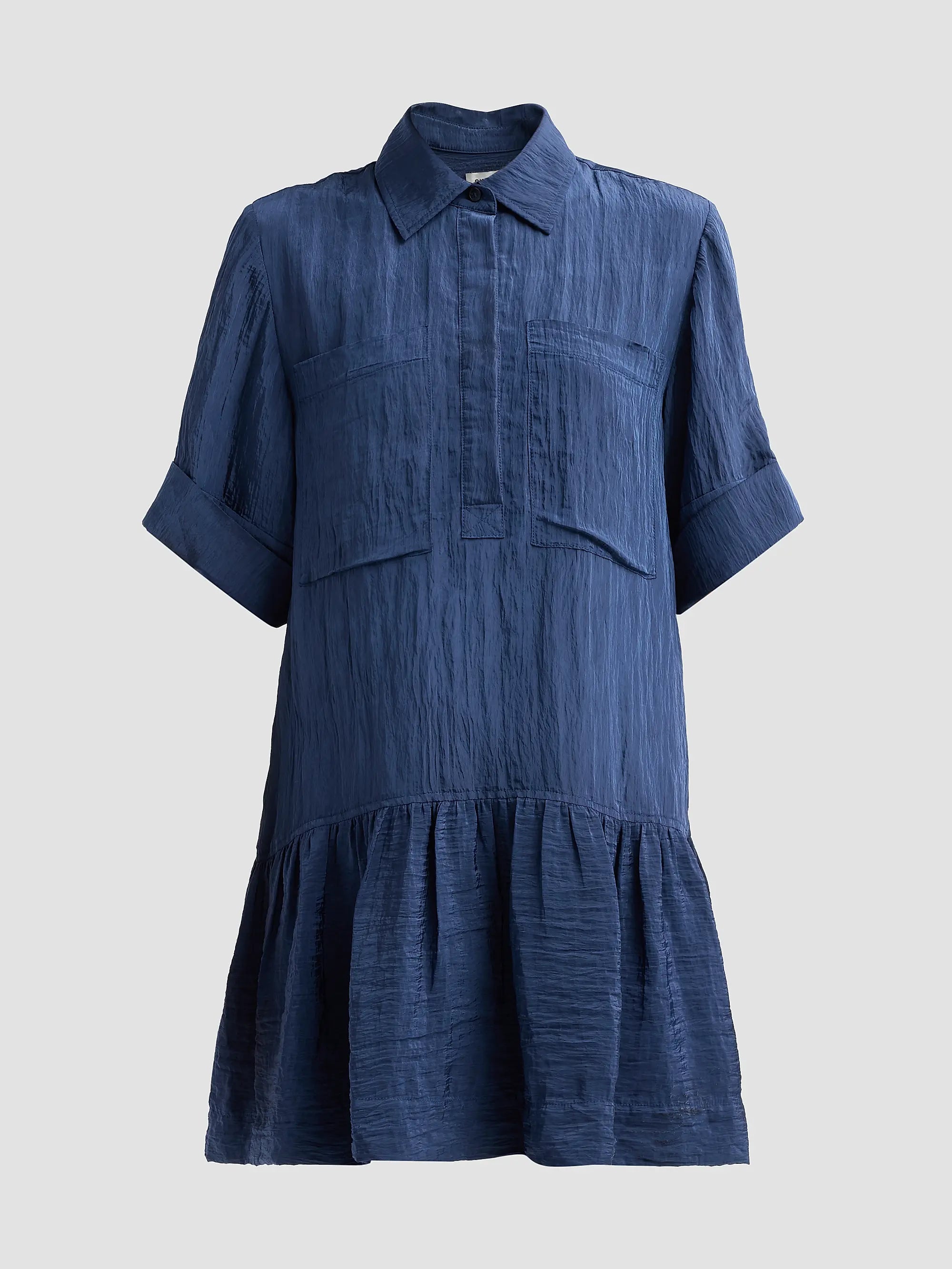 A blue crinkled cotton shirt dress with a pointed collar, short sleeves with rolled cuffs, a buttoned placket, and a tiered ruffle hem, shown against a solid light gray background.
