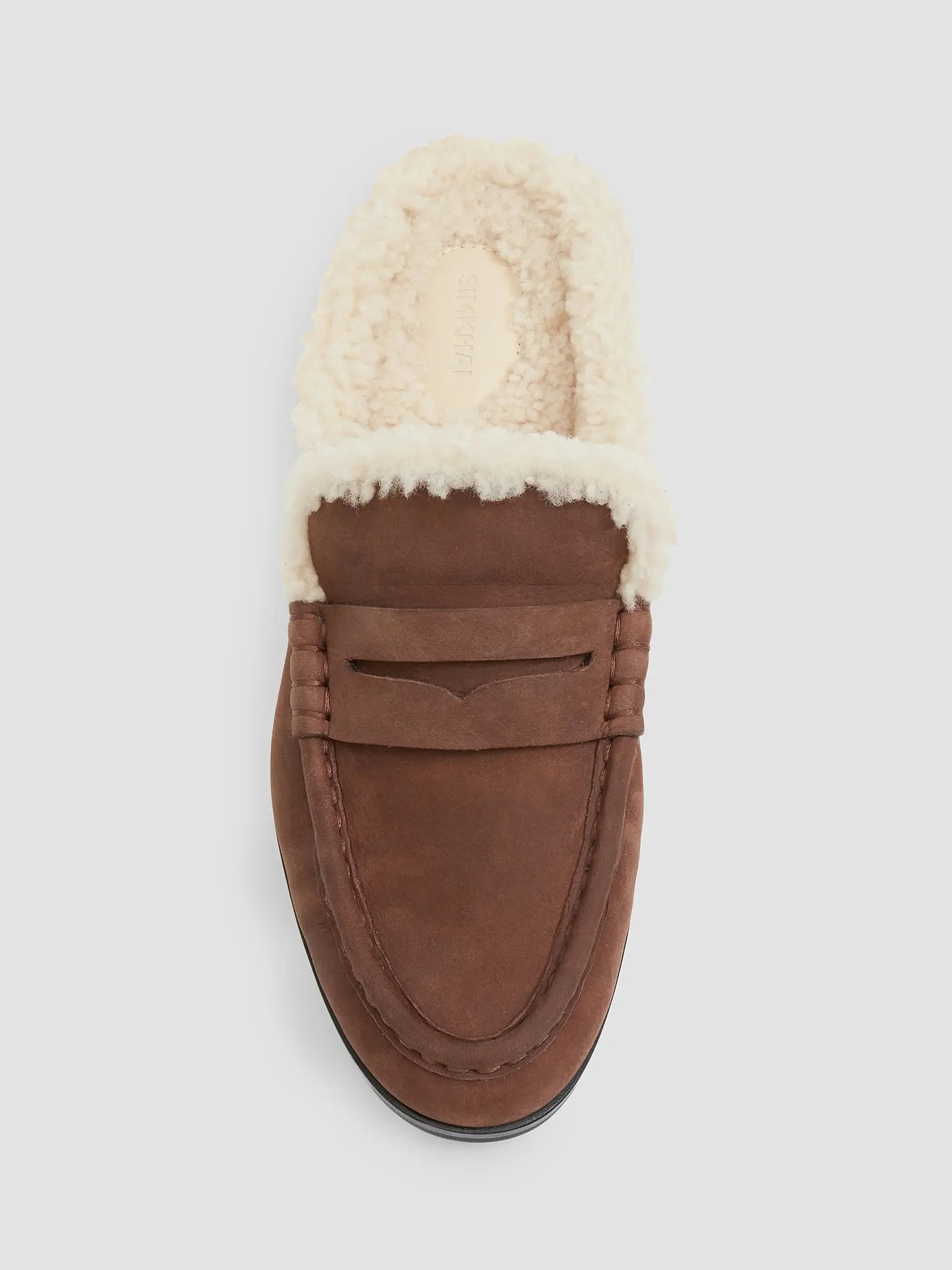 A single brown suede slip-on loafer with a thick cream-colored shearling lining, shown from a top-down view on a light gray background.