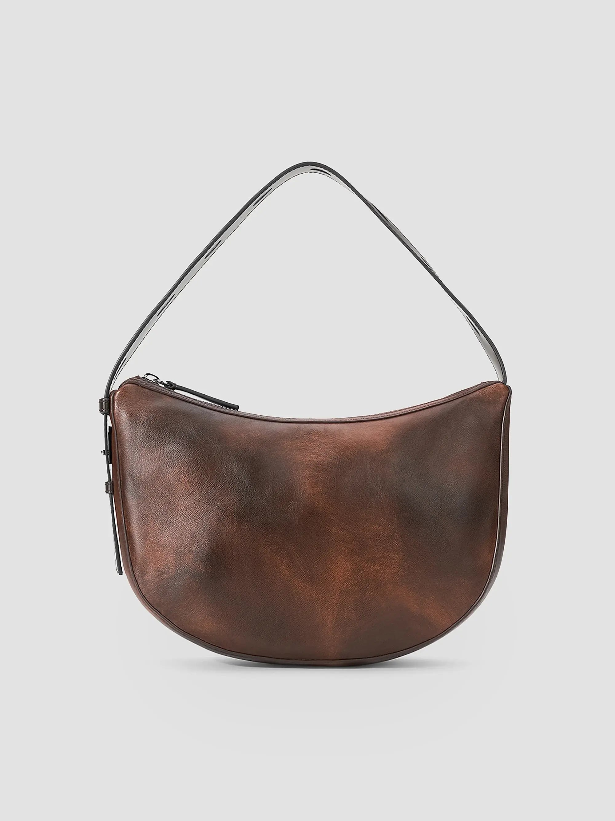 A brown leather crescent-shaped shoulder bag with a single thin strap and a zippered top, shown against a light gray background.