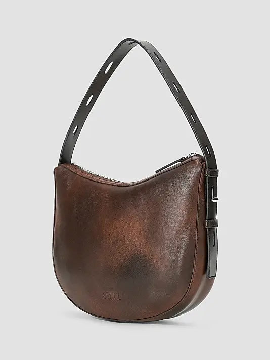 A brown leather crescent-shaped shoulder bag with a black adjustable strap and a subtle embossed logo on the front, set against a light gray background.