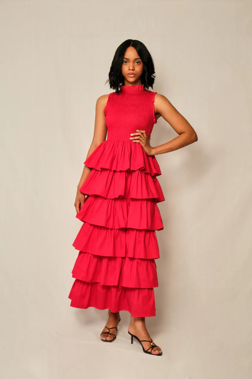 Woman wearing a red tiered dress against a beige background