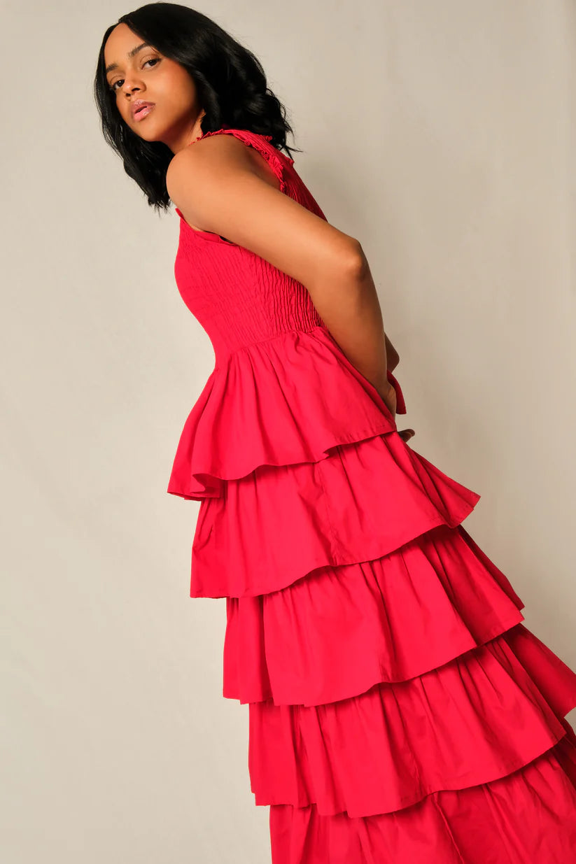 Woman wearing a red tiered dress against a plain background