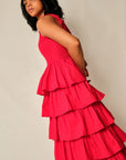 Woman wearing a red tiered dress against a plain background