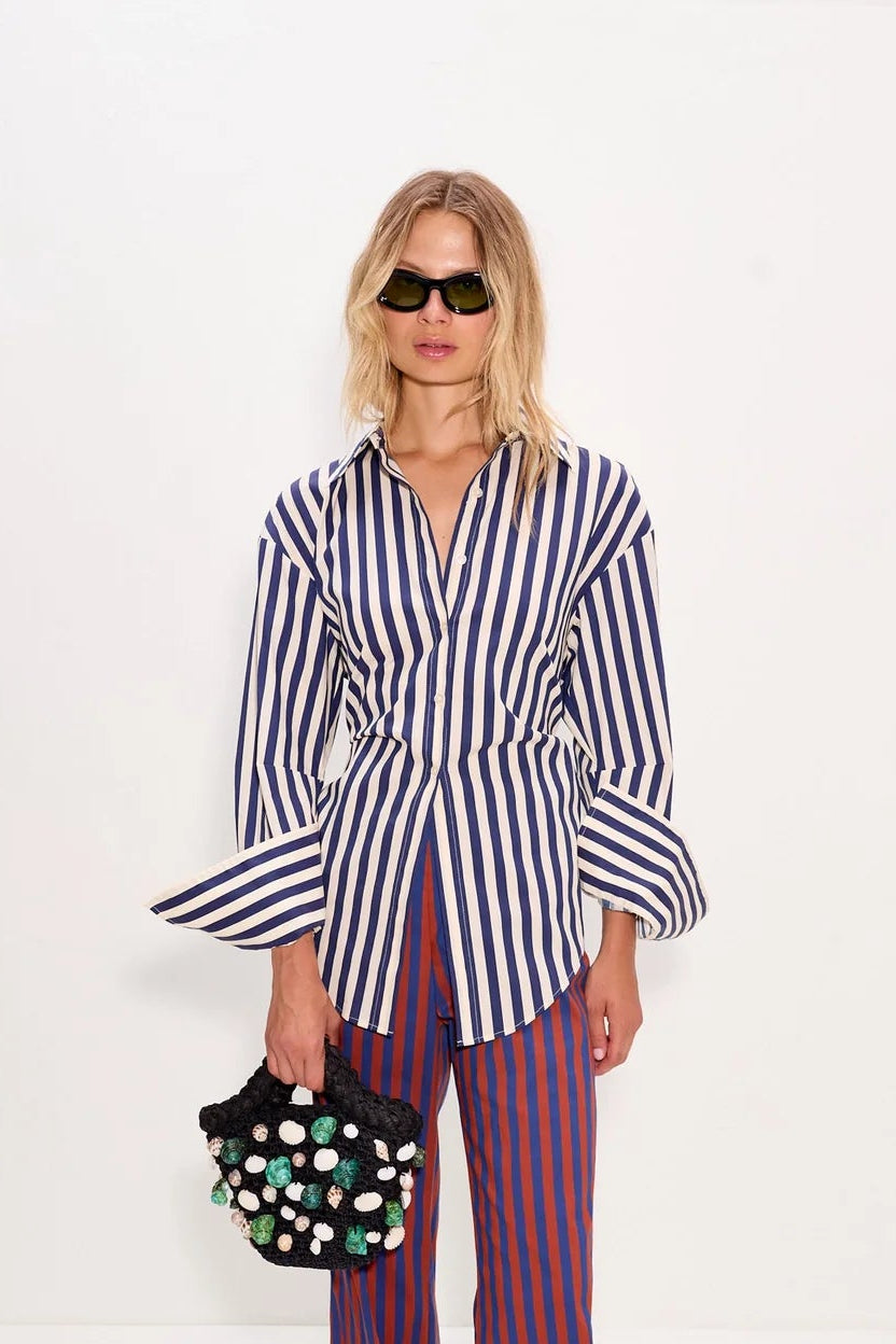 Woman wearing a striped shirt and pants with a polka dot bag on a white background