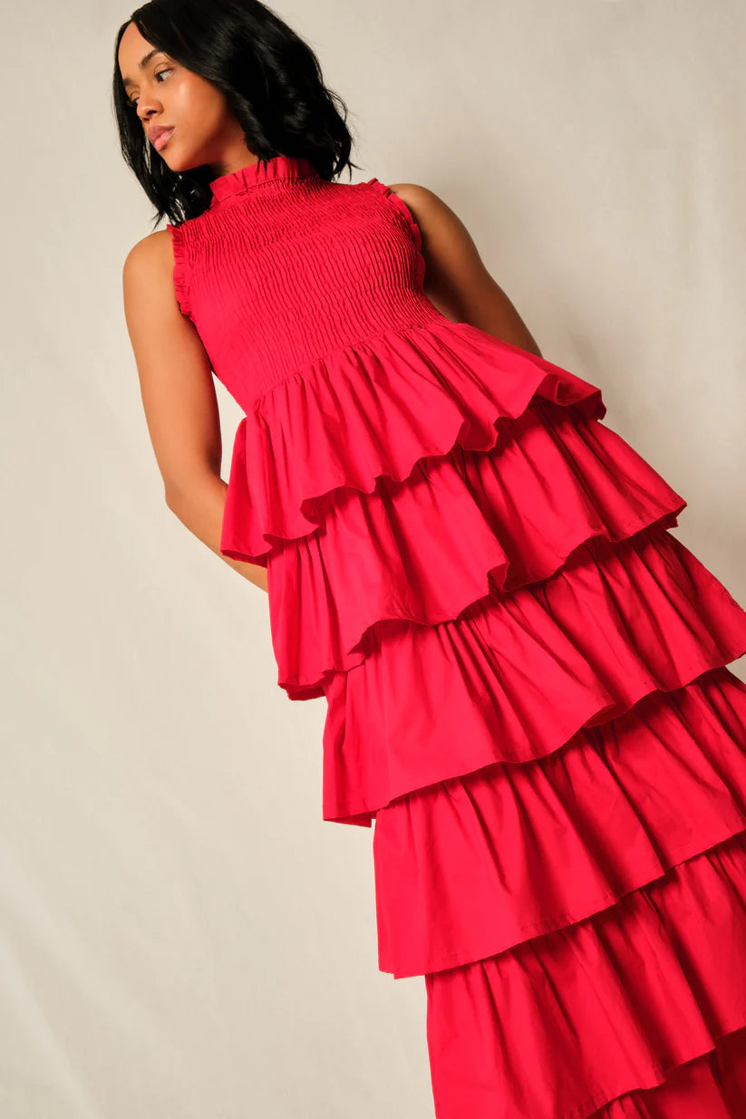 Woman wearing a bright pink, tiered dress against a plain background