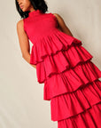 Woman wearing a bright pink, tiered dress against a plain background