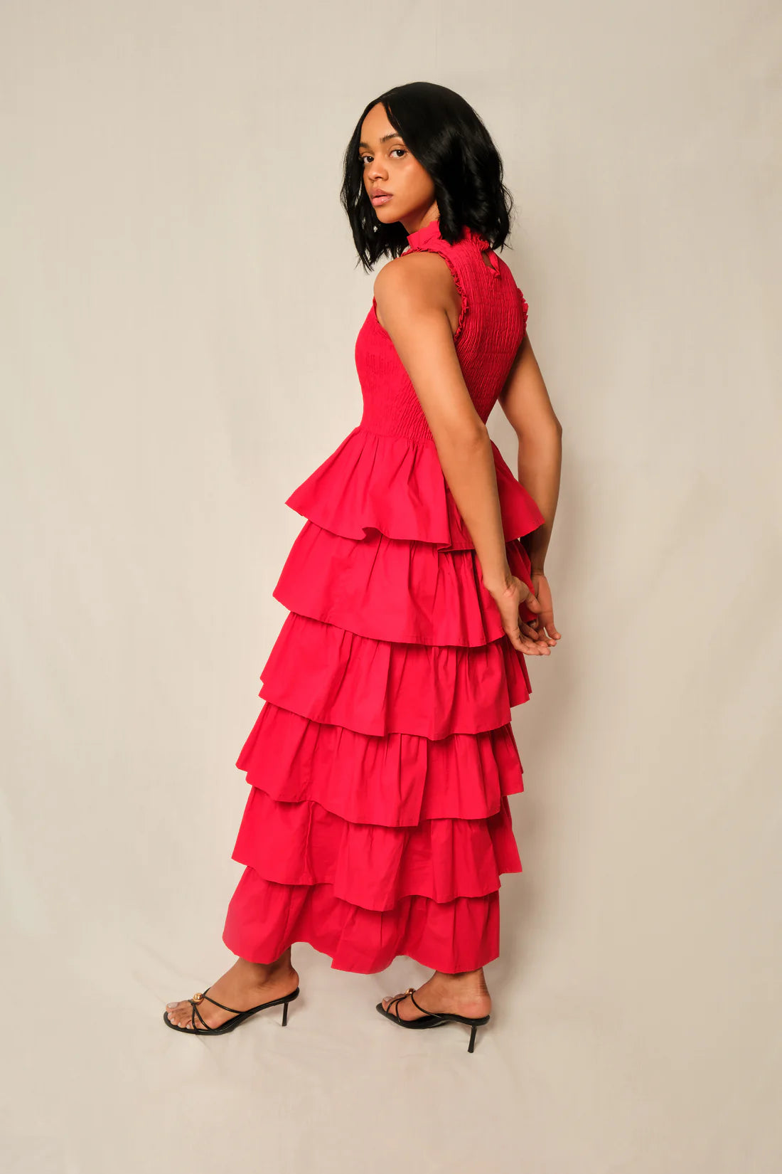 Woman wearing a red tiered dress against a plain background