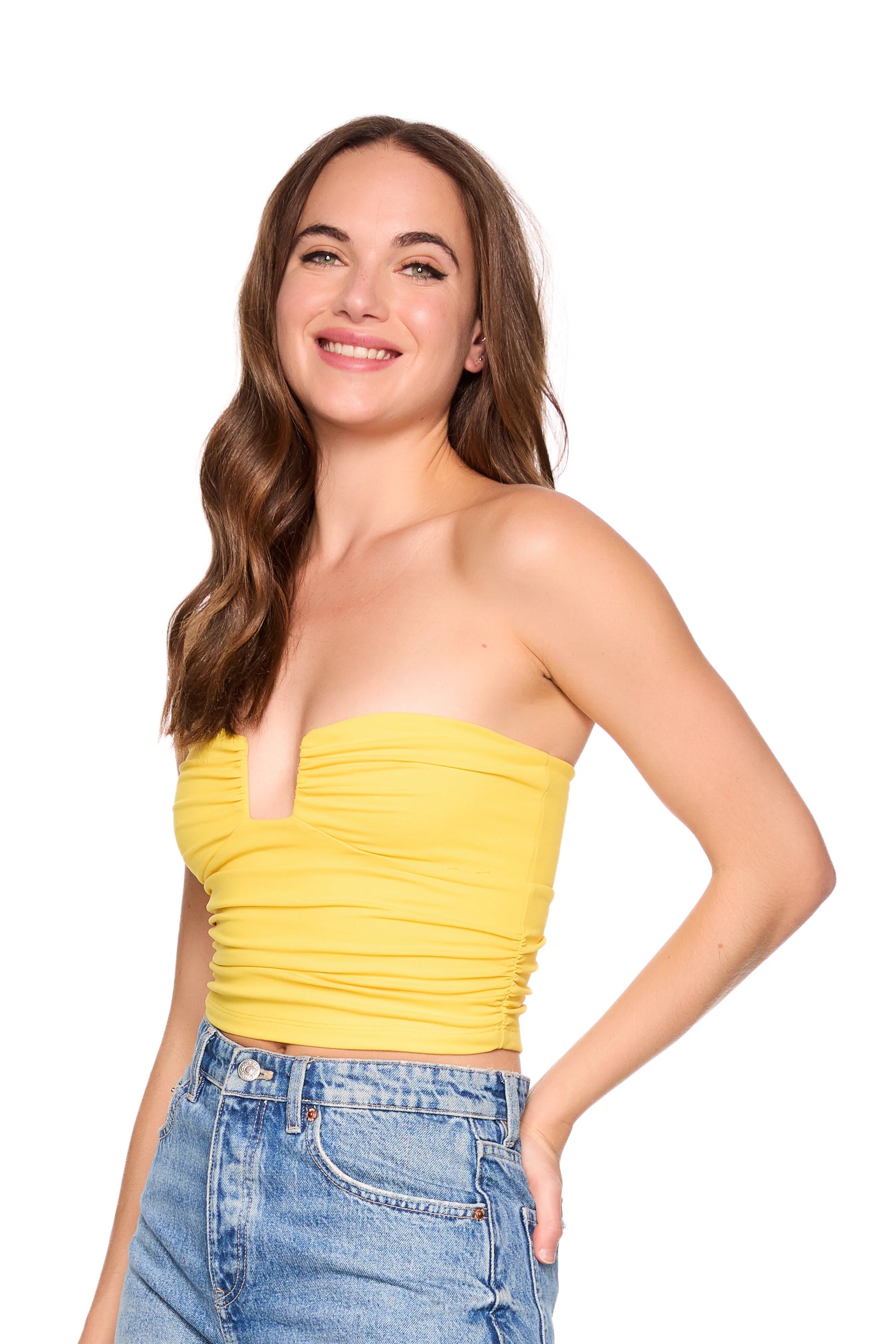 Woman wearing a yellow strapless top and blue jeans on a white background