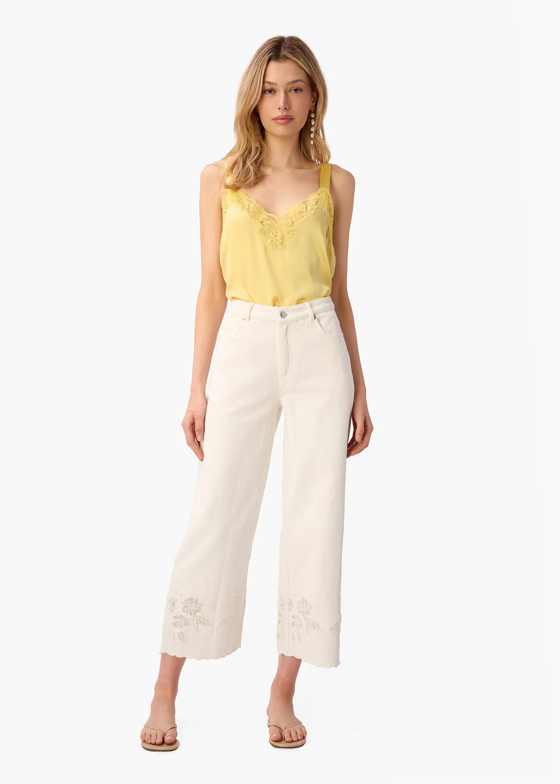 Woman wearing a yellow top and white pants on a white background