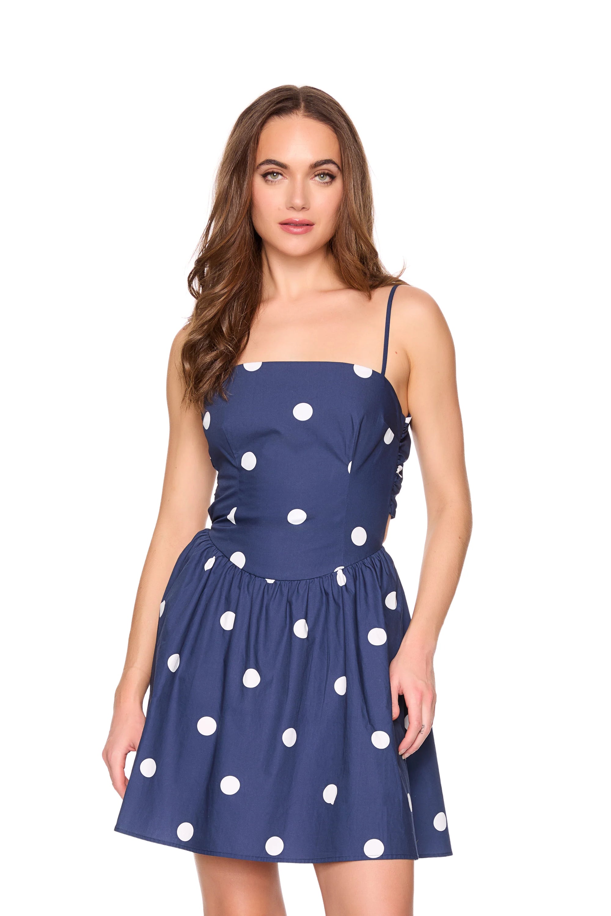 Woman wearing a navy blue dress with white polka dots on a white background