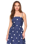 Woman wearing a navy blue dress with white polka dots on a white background