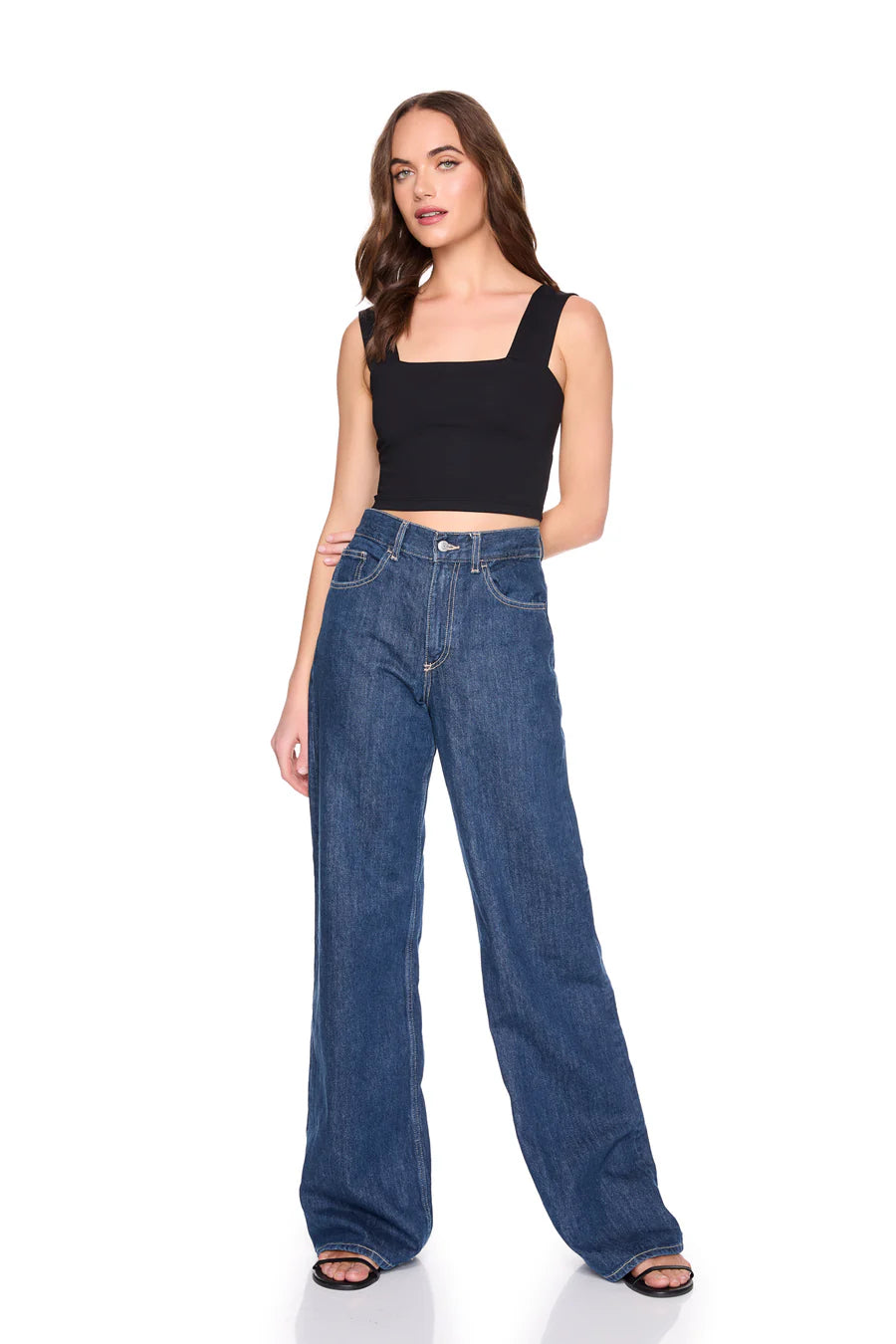 Woman wearing blue jeans and a black top on a white background, full body front