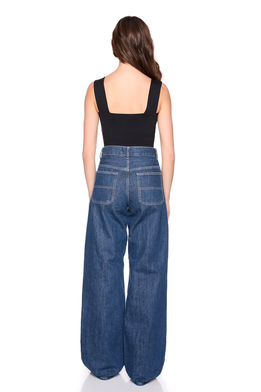 Person wearing blue wide-leg jeans and a black top on a white background, back