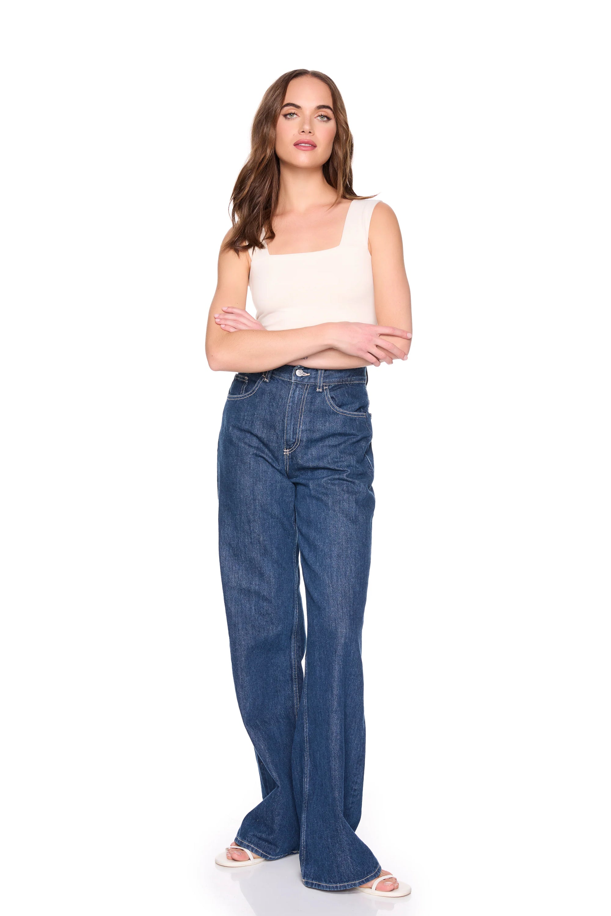 Woman wearing blue jeans and a beige top on a white background