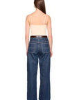 A woman shown from the back wearing dark blue wide-leg jeans, a brown belt, and a light beige camisole top against a plain white background.