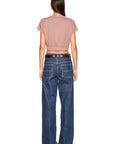A woman shown from the back wearing a short-sleeve cropped taupe top and wide-leg blue jeans with a dark brown belt, against a plain white background.
