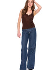 A woman modeling a brown ribbed tank top with a button henley collar and wide-leg blue jeans, standing against a plain white background.