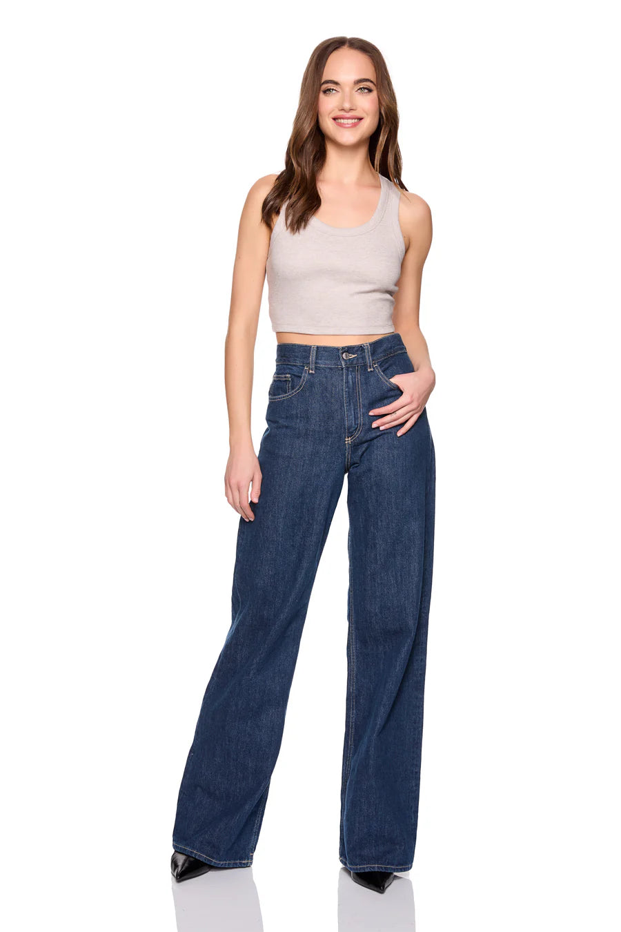 Woman wearing blue jeans and a beige top on a white background