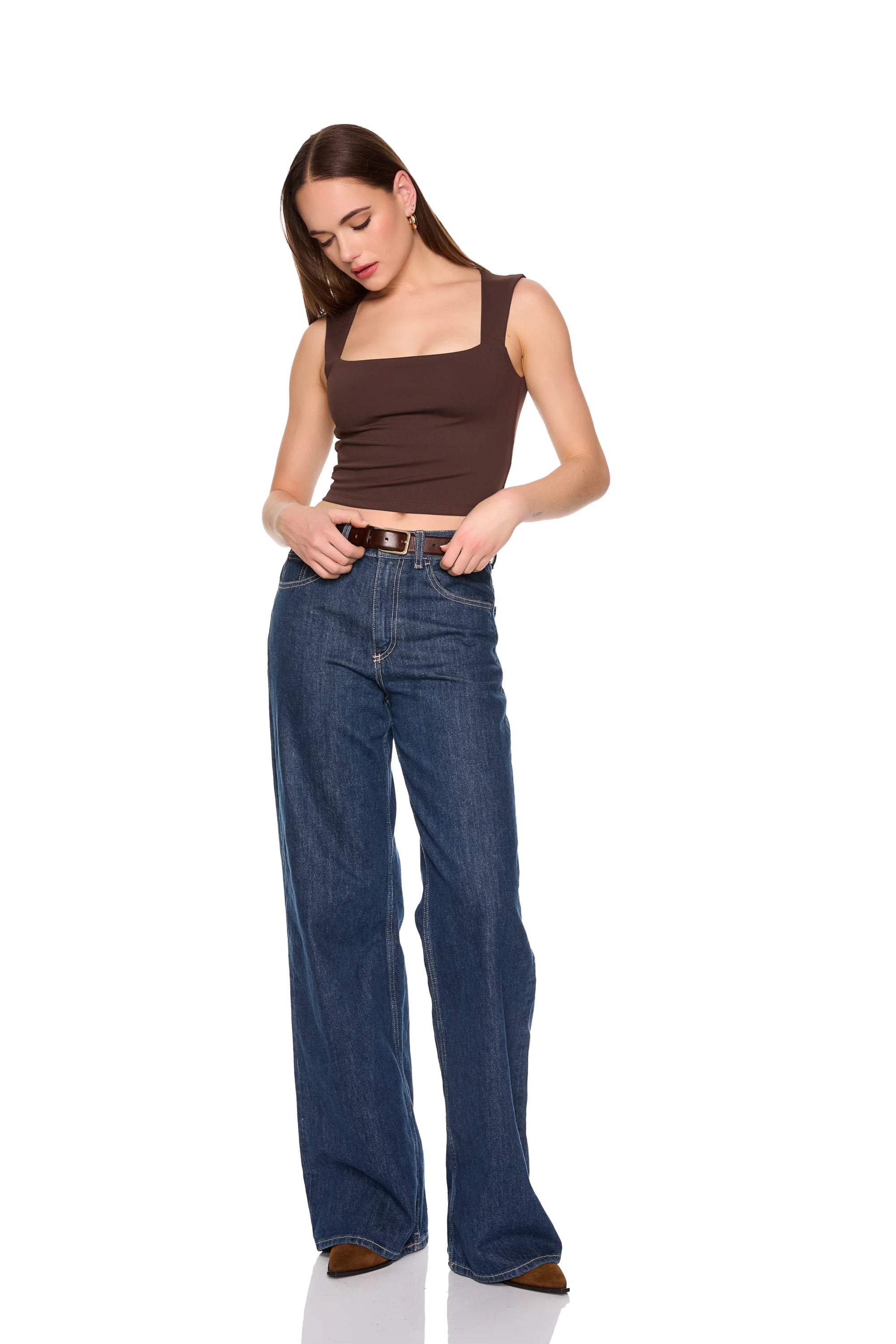 A woman modeling a brown square-neck crop top and wide-leg blue jeans with a brown belt, standing against a solid white background. full body front