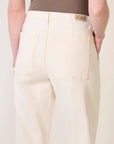 model wearing a bone colored utility jean / pant with a brown tank on a white background, back view