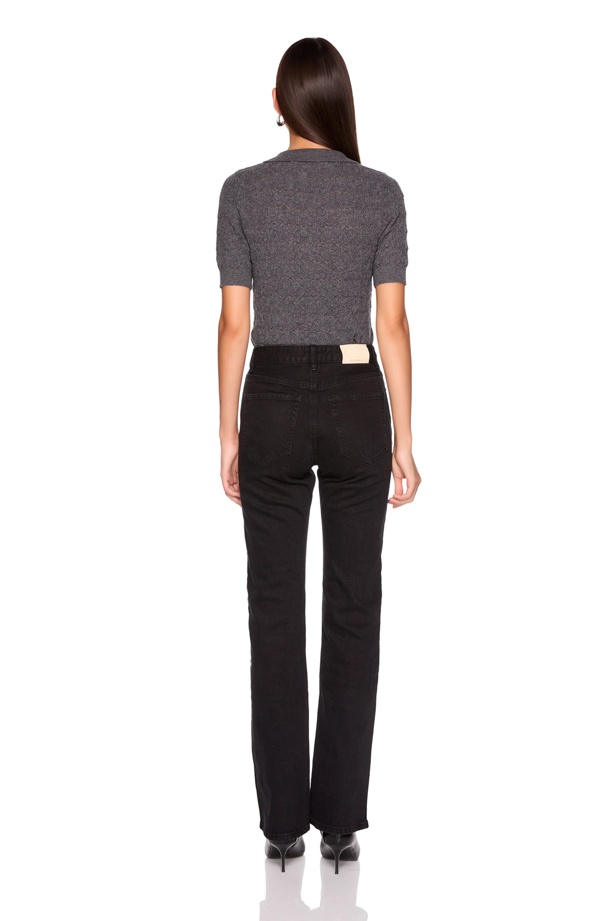 A woman shown from the back wearing a short-sleeve textured gray top and black pants against a plain white studio background.