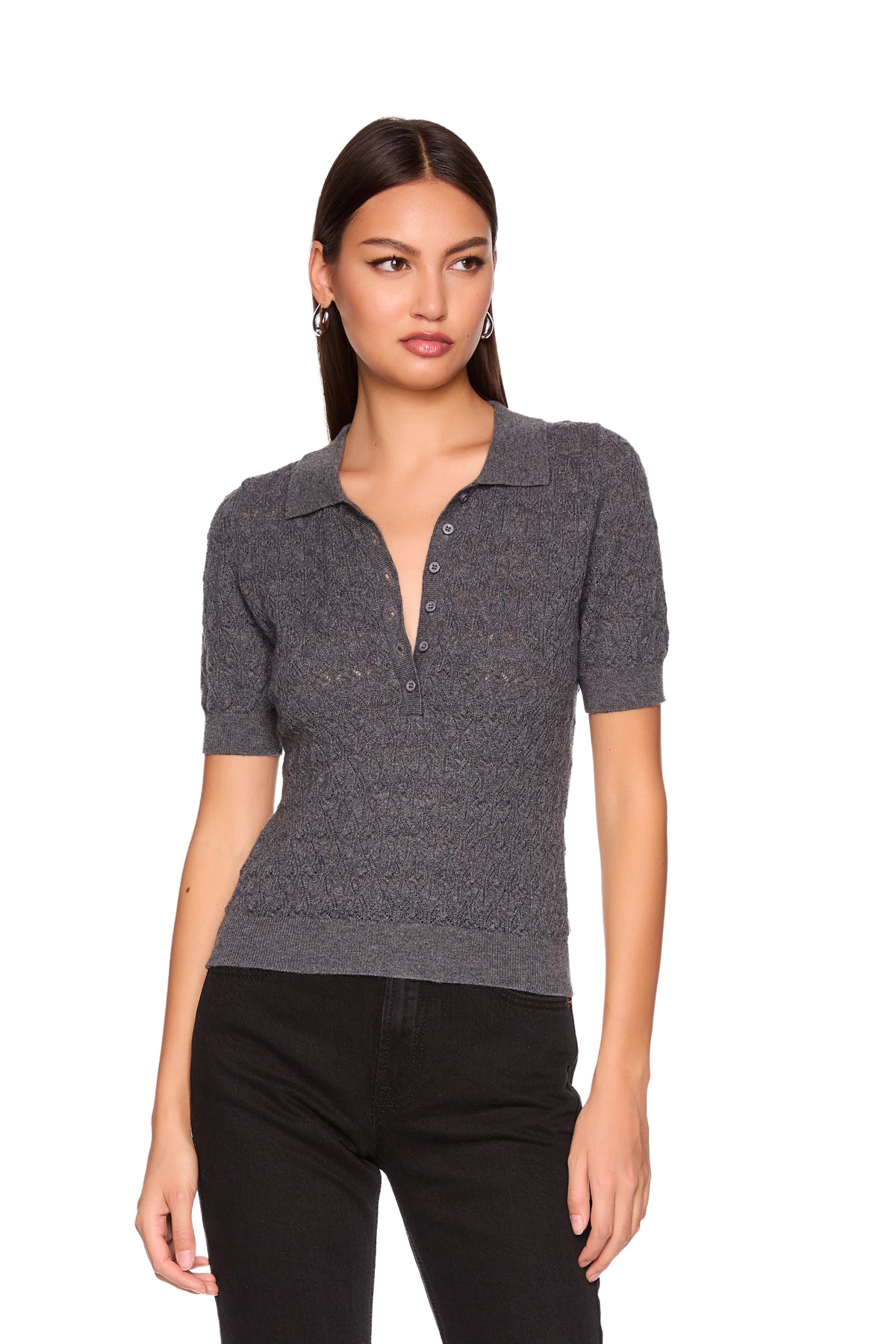 A woman modeling a short-sleeve knit polo shirt in dark gray with a subtle textured pattern, paired with black pants, against a plain white background.