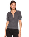 A woman modeling a short-sleeve knit polo shirt in dark gray with a subtle textured pattern, paired with black pants, against a plain white background.