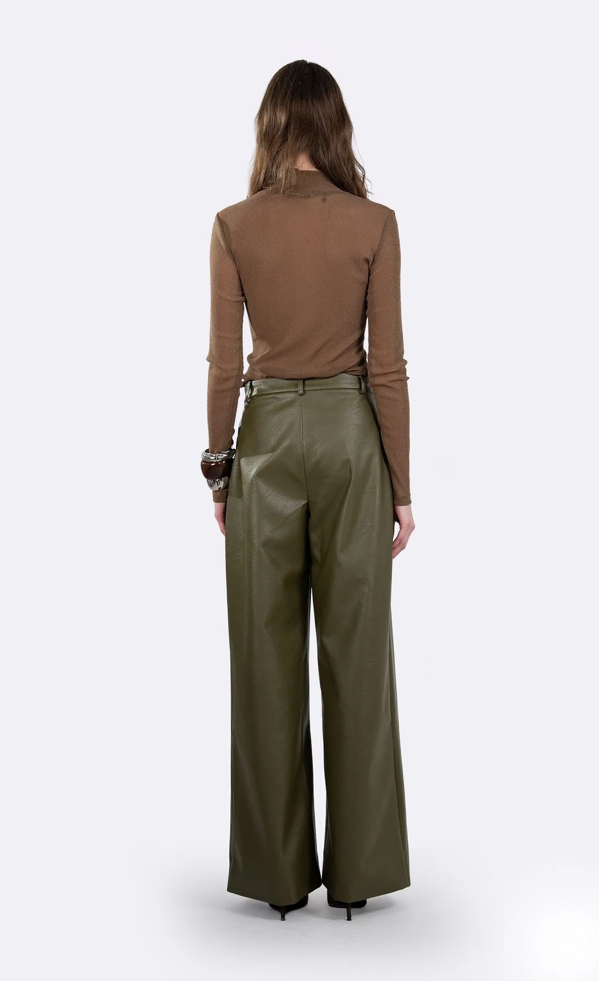 A model shown from the back wearing a brown long-sleeve top and olive green wide-leg trousers against a light gray studio background.