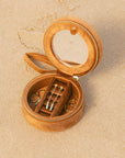 Open  jewelry box with small items on a beige sand background