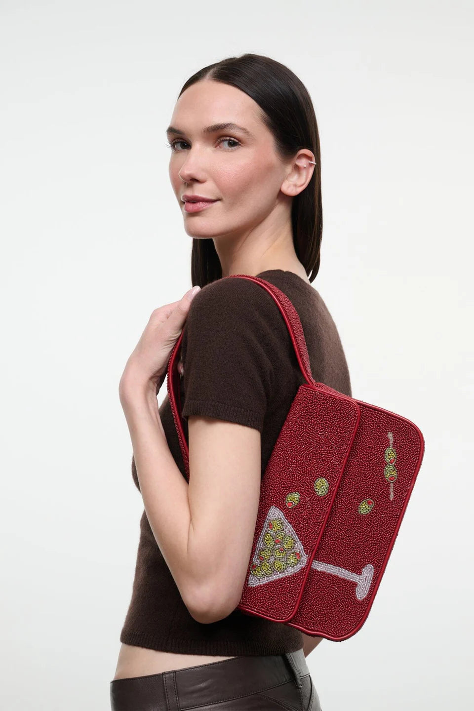 A woman wearing a brown short-sleeve top and dark leather pants carries Tommy Beaded Bag Extra Dirty