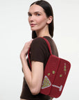 A woman wearing a brown short-sleeve top and dark leather pants carries Tommy Beaded Bag Extra Dirty
