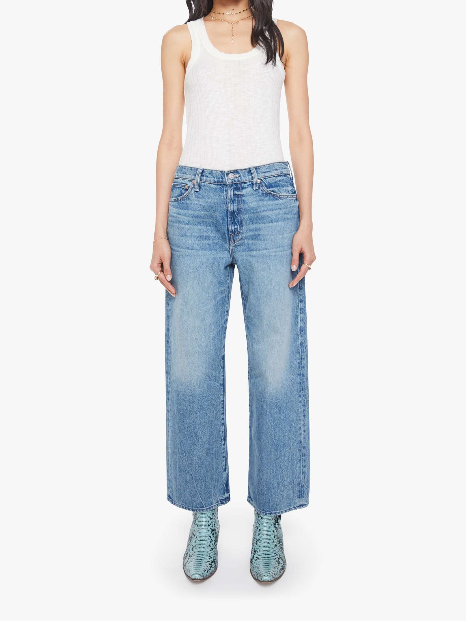 Woman wearing a white tank top and blue jeans on a white background