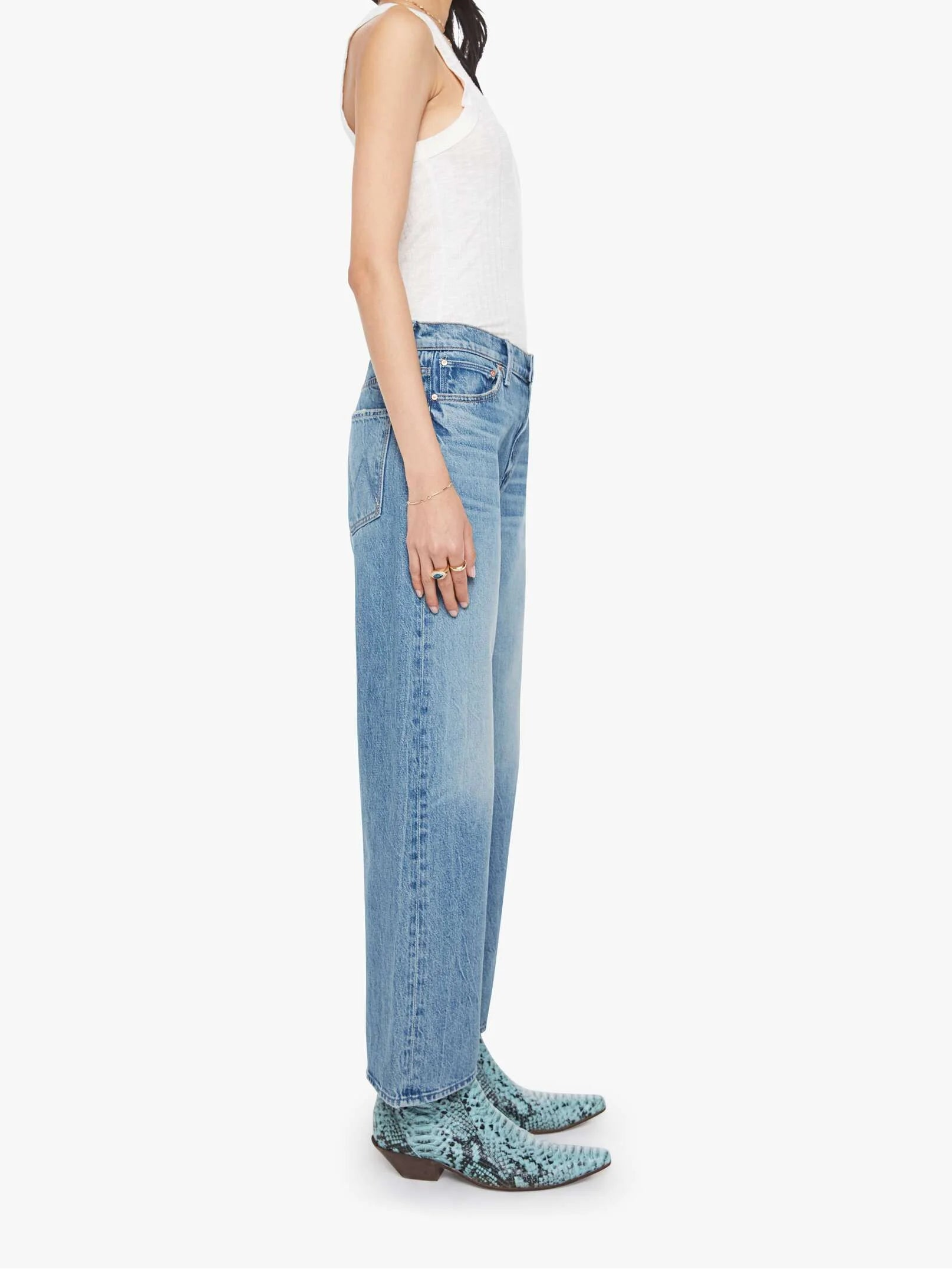 Woman wearing light blue jeans and a white top on a white background