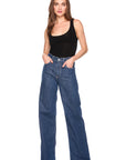 Woman wearing blue jeans and a black tank top on a white background