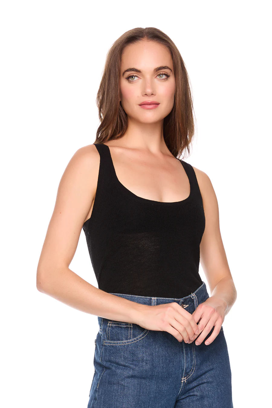 Woman wearing a black tank top and blue jeans on a white background