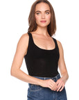 Woman wearing a black tank top and blue jeans on a white background