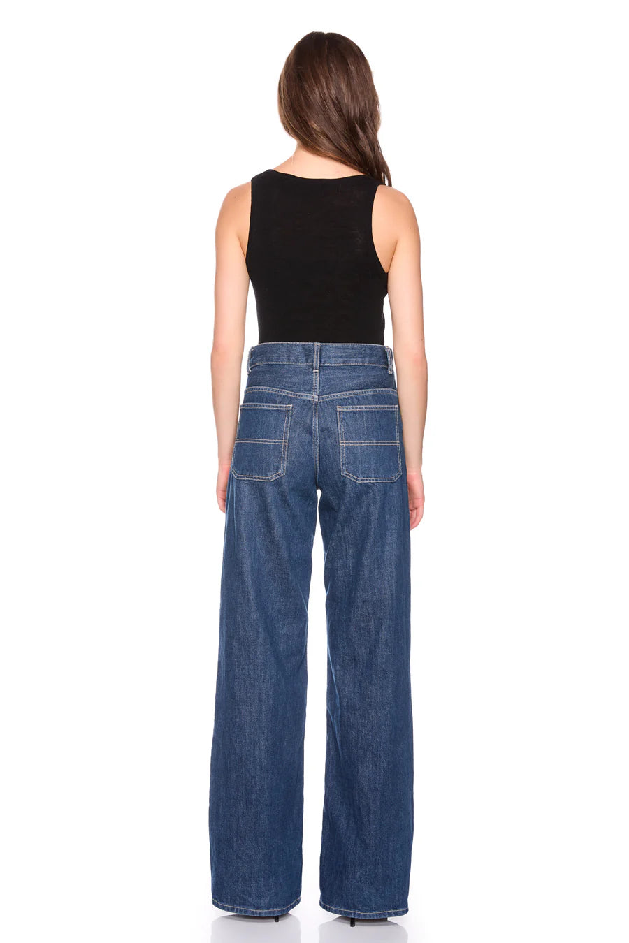 Woman wearing blue jeans and a black top on a white background