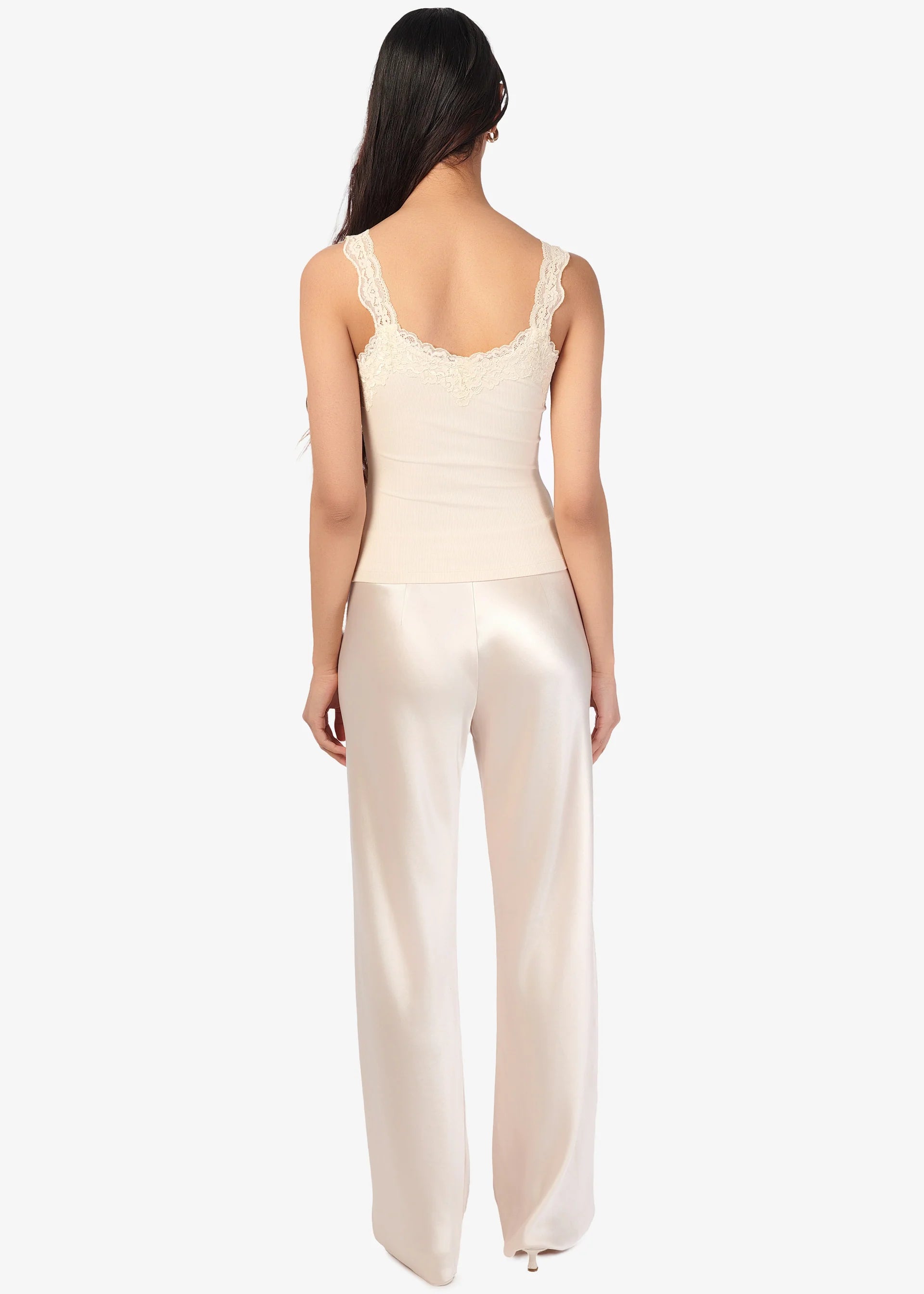 Woman wearing a cream-colored satin jumpsuit on a white background