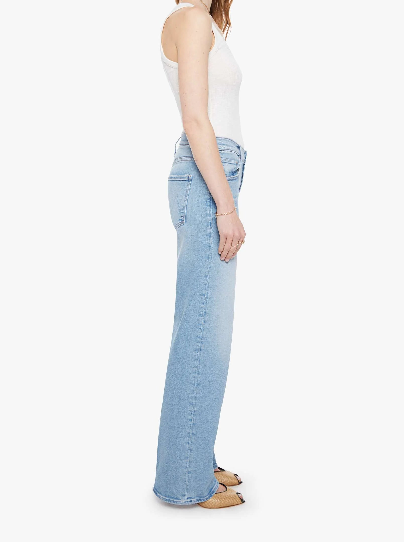 Woman wearing light blue jeans and a white top on a white background
