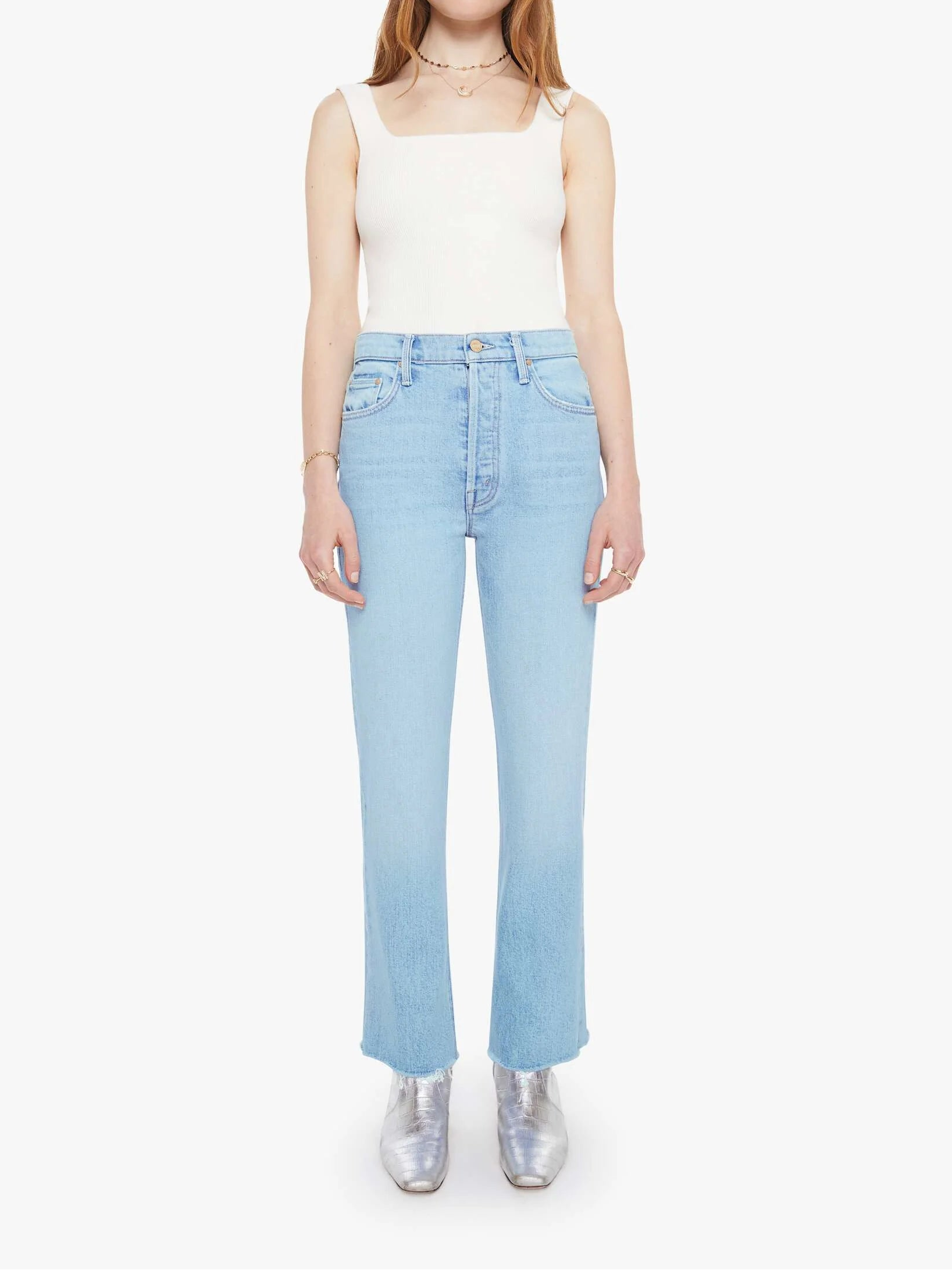 Woman wearing a white sleeveless top and light blue jeans on a white background front view