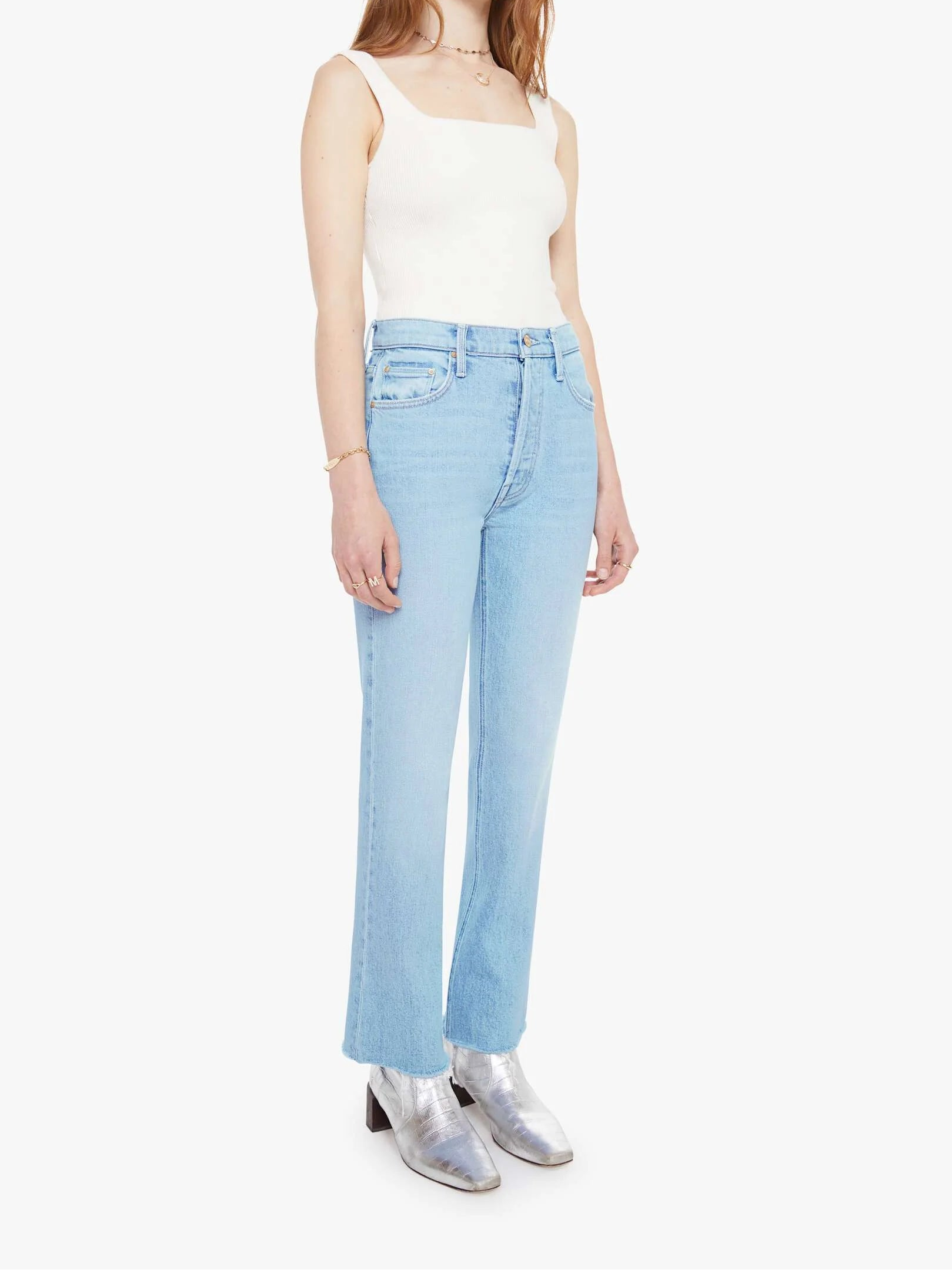 Woman wearing light blue jeans and a white top on a white background