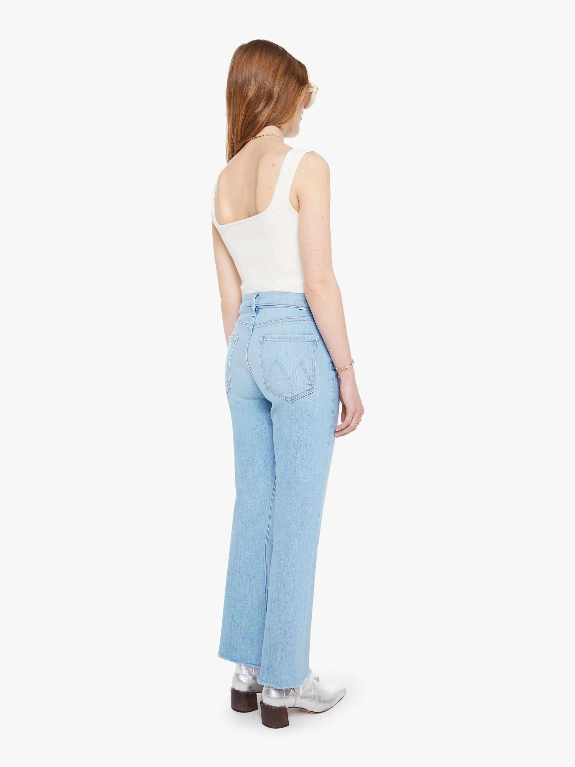 Woman wearing light blue jeans and a white top on a white background