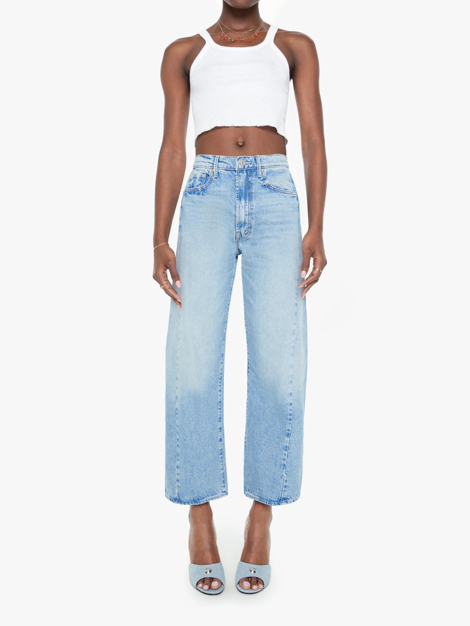 Woman wearing light blue jeans and a white top on a white background, front