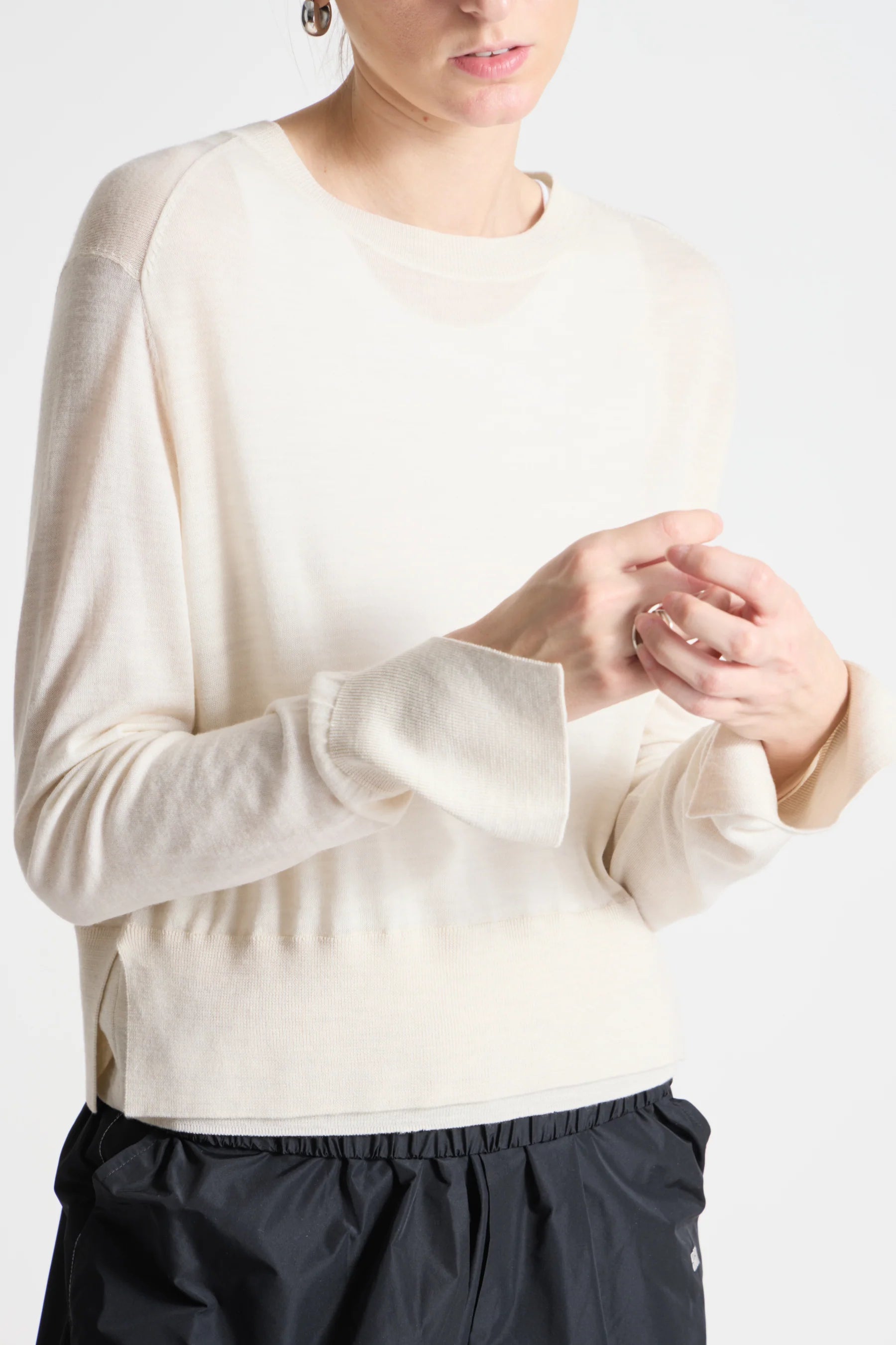 Person wearing a cream sweater and black pants on a white background