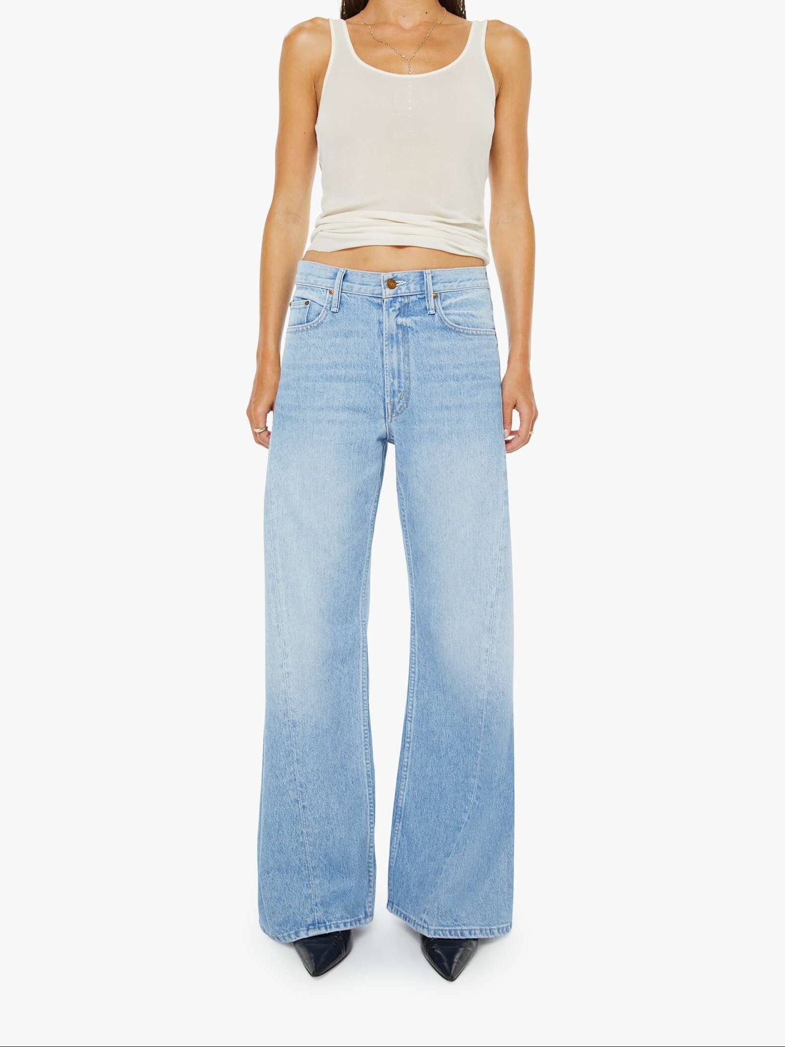 Woman wearing a white tank top and light blue jeans on a white background